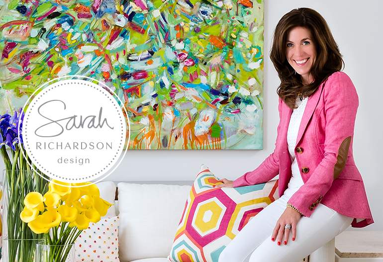 Sarah Richardson, Interior Designer sitting in a room with a bright painting and flowers.